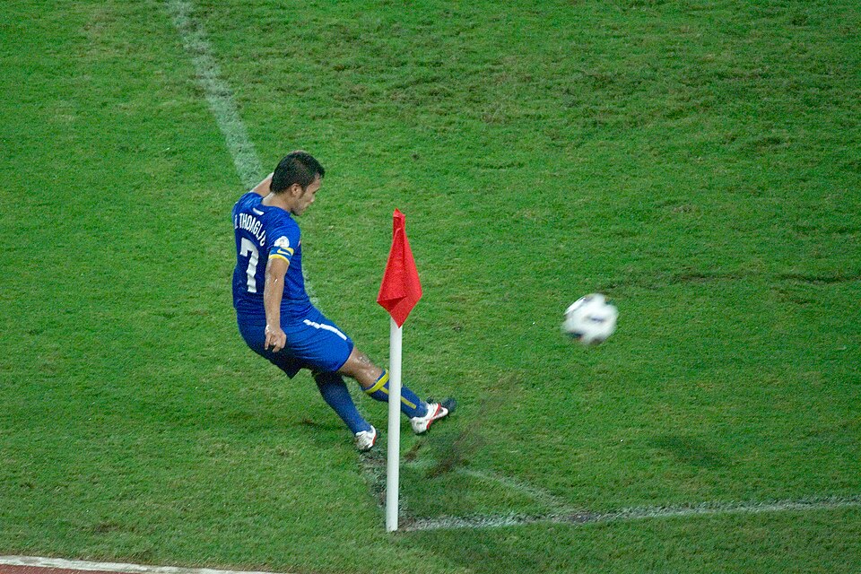 Jugador ejecutando un tiro de esquina en un estadio iluminado